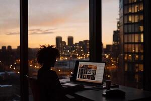 A person sitting at a desk with a laptop computer in front of a window photo