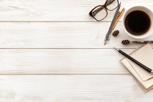 A cup of coffee, pen, notepad, and glasses on a wooden table photo