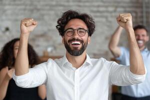 A man with glasses and a beard is celebrating with his arms up photo
