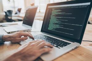 A person typing on a laptop computer with code on it photo