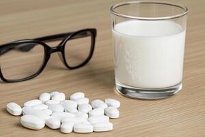 A glass of milk and glasses of pills on a table photo