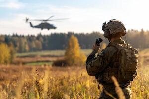 A soldier is looking at a helicopter in the background photo