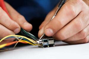 A person is working on a wire with a tool photo