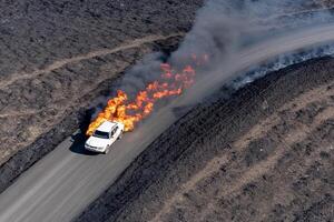 A car is on fire in the middle of a road photo