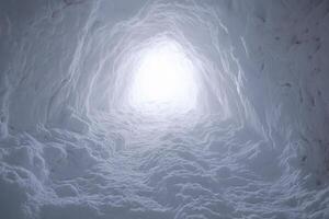 A tunnel with snow and light coming out of it photo