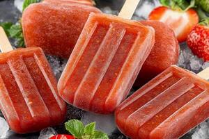 Three popsicles with strawberries and mint on ice photo