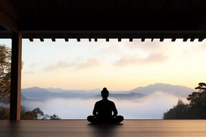 A person sitting in meditation in front of a mountain view photo