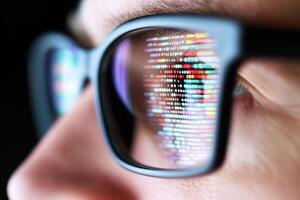 Close up of a man wearing glasses with a computer screen photo