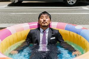 A man in a suit and tie sitting in an inflatable pool photo