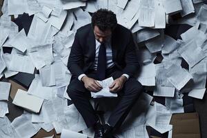 A man in a suit sitting on top of a pile of papers photo