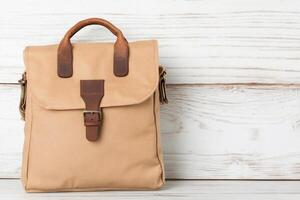 A tan leather backpack on a white wooden background photo