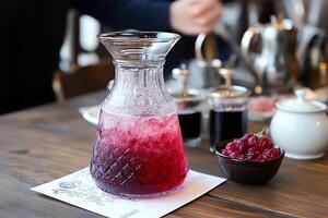 A pitcher of raspberry juice sits on a table photo