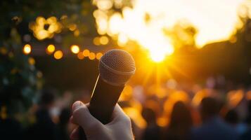 A Hand Holds a Microphone Amidst a Golden Sunset photo