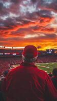 Captivating Stadium View Fan Engrossed in Game Amidst Fiery Sunset - Experience the Thrill of the Sport and the Beauty of the Sky. photo