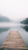 Serene Lake Landscape with Wooden Pier in Misty Mountains A Tranquil Nature Scene with Fog, Calm Waters, and Reflections on a Peaceful Morning photo
