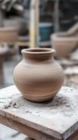 Earthenware Vessel A Handmade Clay Pottery on a Rustic Table, Evoking Traditional Craftsmanship and Artistic Skill in a Blurred Studio Background photo