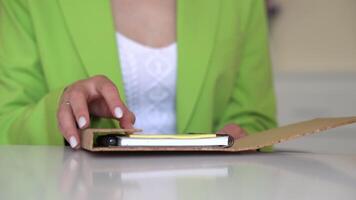 A woman in a green jacket is holding a notebook video