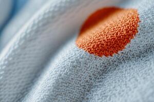 A close up of a white towel with an orange dot photo