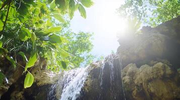 Waterfall in tropical forest with sun shining through photo