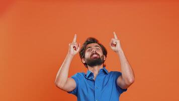 Young man showing thumbs up and pointing at left on blank space, place for your advertisement logo video