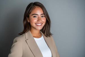 Professional portrait of a smiling woman in a beige blazer against a gray background photo