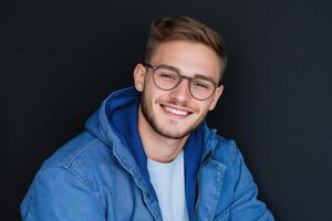 Young man smiling in casual attire against a dark background photo