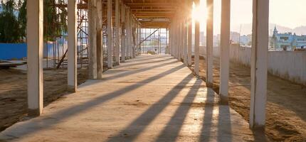 A walkway with concrete pillars and a sun setting photo