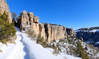 A trail leads up to a cliff with snow on it photo