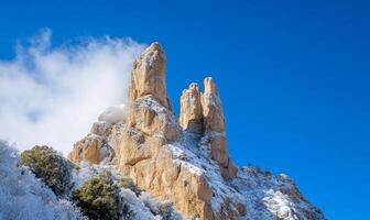 Snowy mountains in the desert with trees and clouds photo