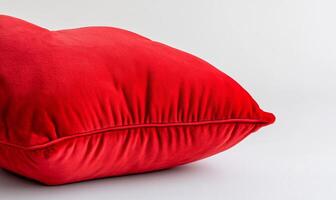 A plush red pillow resting on a neutral background. photo