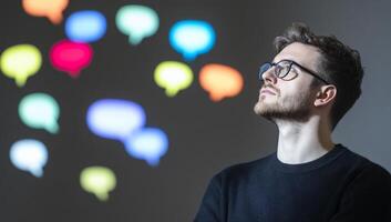A contemplative man gazes at colorful speech bubbles in a thoughtful scene. photo