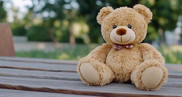A plush teddy bear sitting on a wooden table in a park setting. photo