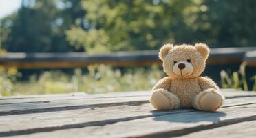 A plush teddy bear sits on wooden planks in a serene outdoor setting. photo