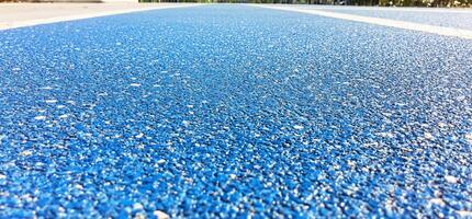 Close-up of a blue sports track surface with white lane markings. photo
