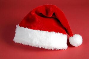 A classic red Santa hat with a white fluffy brim and pom-pom. photo
