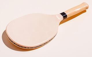 Close-up view of a light beige pickleball paddle resting on a smooth surface in bright lighting photo
