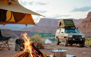 Enjoying a cozy rustic camping setup with a campfire and an SUV near a scenic river at sunset photo