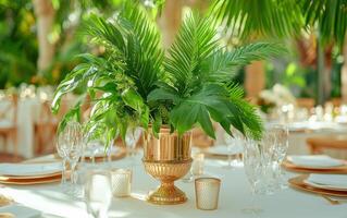 Elegant event table setting featuring lush greenery and golden accents in a tropical venue photo