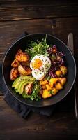 Colorful farm to table bowl featuring roasted vegetables, fresh greens, and a sunny side up egg in a rustic setting photo