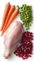 Raw chicken leg with fresh carrots, green peas and pomegranate seeds arranged on white background photo