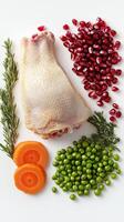 Raw chicken leg with herbs, green peas, carrots, and pomegranate seeds on a white background photo