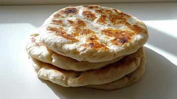 Freshly baked naan bread stacked on white surface photo