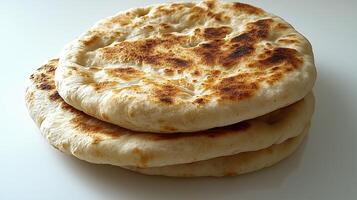 Freshly baked naan bread stacked on a white plate photo