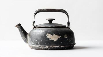 Vintage black teapot with a worn finish on a plain background photo