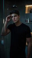 Pensive young man in a black shirt standing in a modern bathroom with a thoughtful expression photo