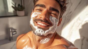 Happy young man applying shaving cream with a smile while enjoying morning routine in bright bathroom photo
