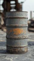 Rusty metal barrel with orange stains in an abandoned industrial setting photo
