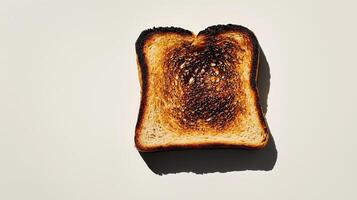 Single slice of burnt toast with charred edges on a plain background photo