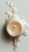 Melted white candle with dripping wax on a neutral surface photo