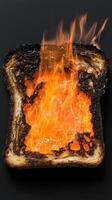 Burnt toast with flames erupting from the center on a black background photo